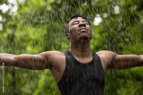 Quadro su tela African man enjoying fresh summer rain while hands raised