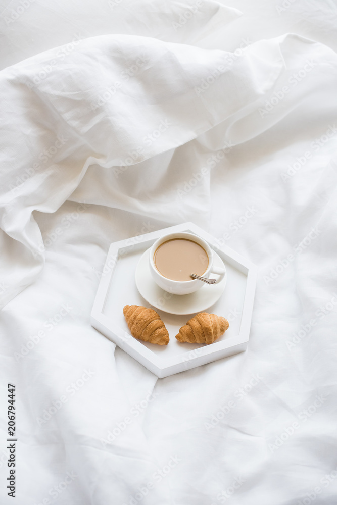 Early morning breakfast in bed, coffee and croissant on the tray Early morning breakfast in bed, coffee and croissant on the tray