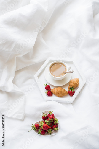 Early morning breakfast in bed, coffee and croissant with strawb