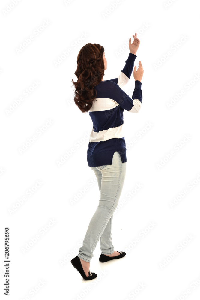 full length portrait of girl wearing striped blue and white jumper and jeans. standing pose facing away from the camera, on white studio background full length portrait of girl wearing striped blue and white jumper and jeans. standing pose facing away from the camera, on white studio background