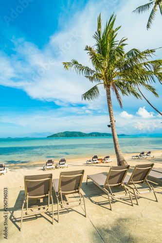 Fototapeta Naklejka Na Ścianę i Meble -  Beautiful tropical beach and sea with coconut palm tree and umbrella and chair in paradise island