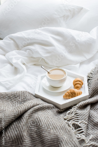Cozy breakfast in bed, cup of coffee and croissants on white and