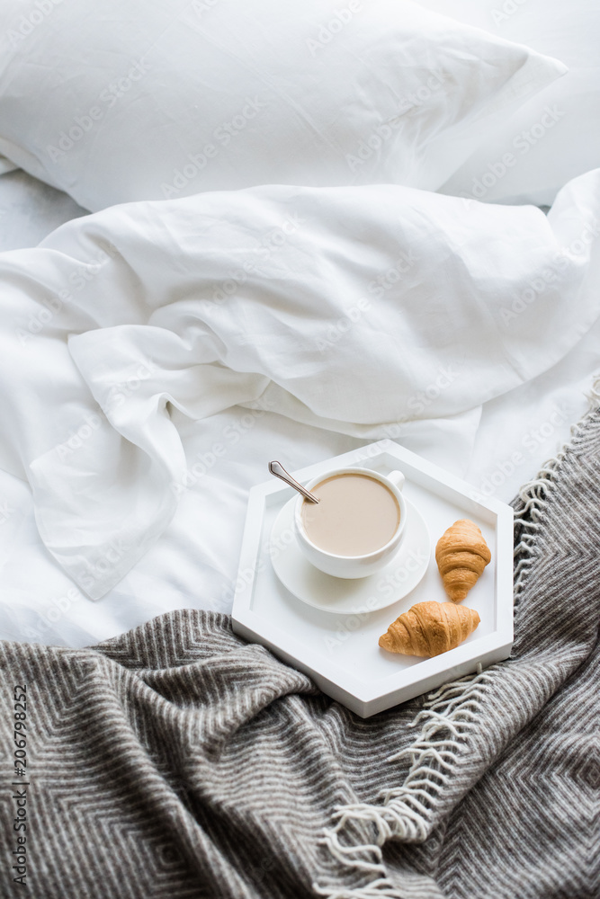 Cozy breakfast in bed, cup of coffee and croissants on white and Cozy breakfast in bed, cup of coffee and croissants on white and