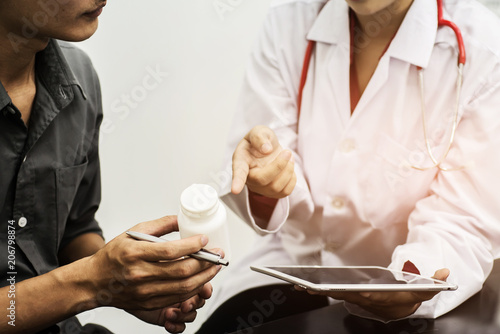 Female medicine doctor hands hold jar of pills and explain the patient how to use dose of pills.