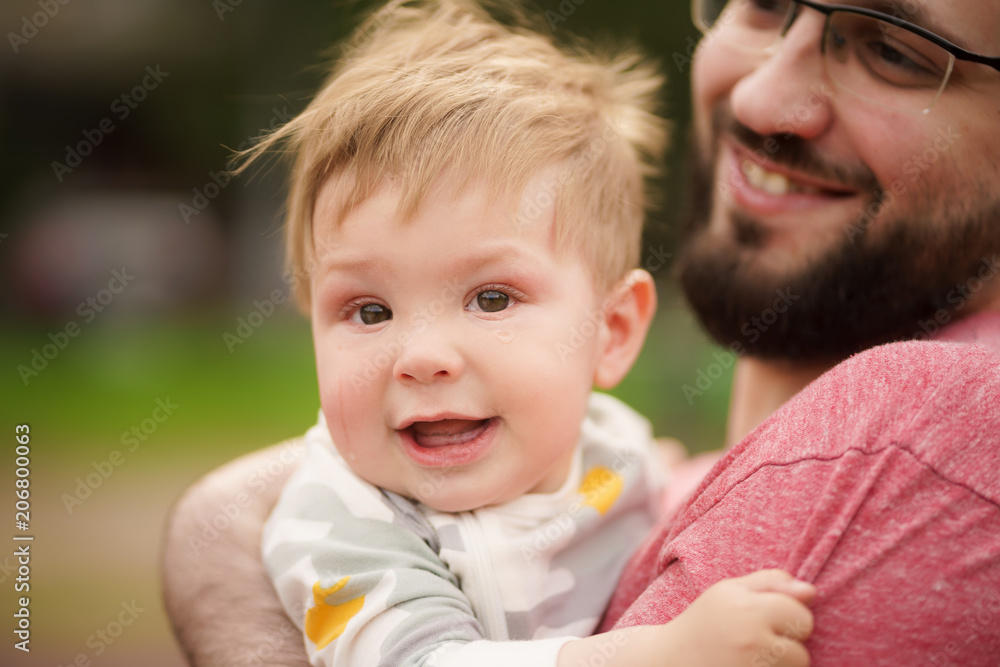 Concept: family values. Close-up portrait of adorable innocent funny brown-eyed baby smiling with his hipster dad. Concept: family values. Close-up portrait of adorable innocent funny brown-eyed baby smiling with his hipster dad.