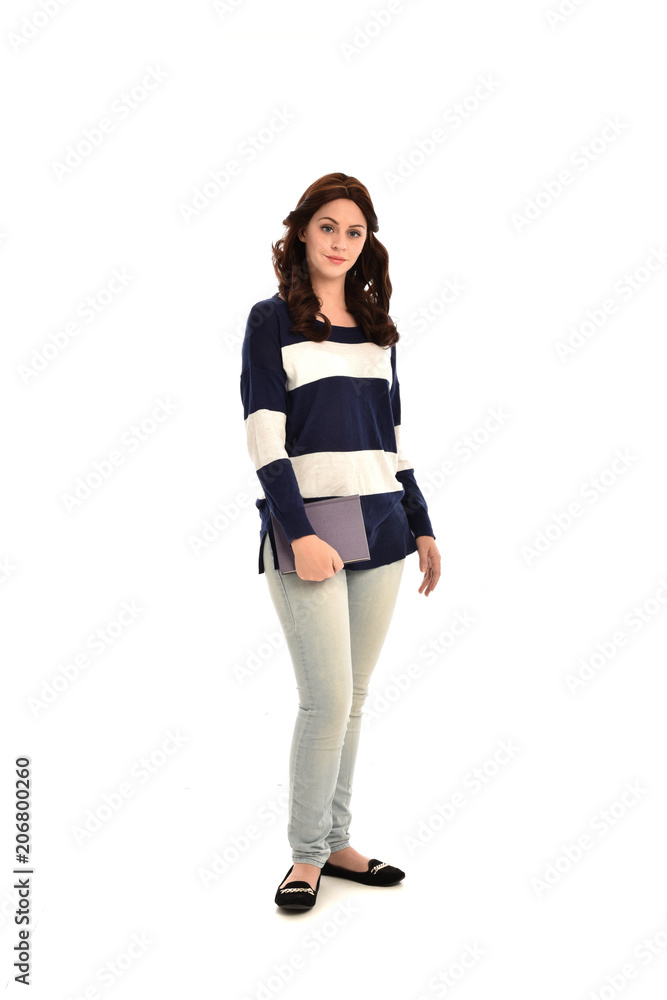 full length portrait of girl wearing striped blue and white jumper and jeans and holding a book. standing pose on white studio background full length portrait of girl wearing striped blue and white jumper and jeans and holding a book. standing pose on white studio background