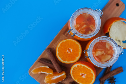 Sweet jam from oranges in small jars with fresh cutted oranges, cinnamon and anice on the blue table
