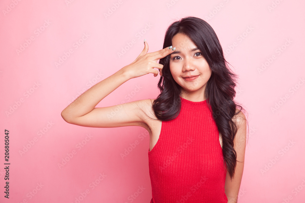 Beautiful young Asian woman holding fingers in gun gesture.