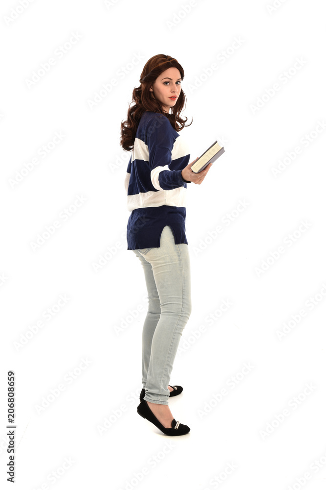 full length portrait of girl wearing striped blue and white jumper and jeans and holding a book. standing pose on white studio background full length portrait of girl wearing striped blue and white jumper and jeans and holding a book. standing pose on white studio background