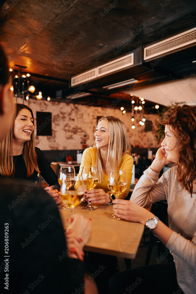 Girlfriends drinking wine and chatting while sitting in the bar. - obrazy, fototapety, plakaty 