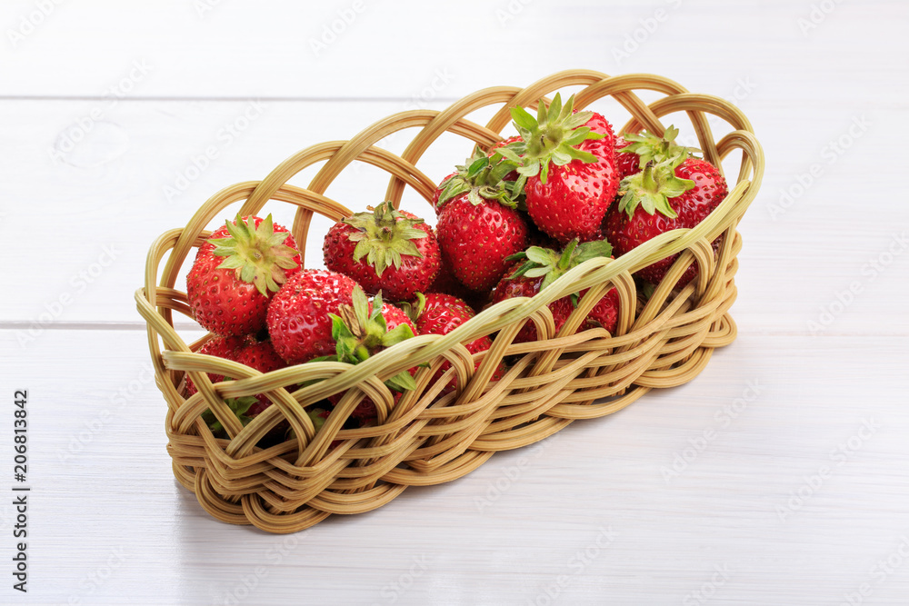 Fresh strawberries in a wicker basket on a white table Fresh strawberries in a wicker basket on a white table