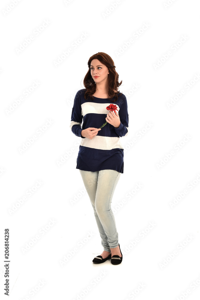 full length portrait of girl wearing striped blue and white jumper and jeans, holding a red flower. standing pose on white studio background full length portrait of girl wearing striped blue and white jumper and jeans, holding a red flower. standing pose on white studio background