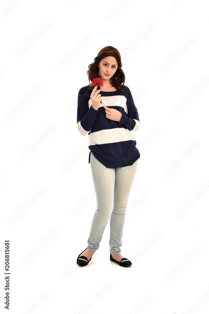 full length portrait of girl wearing striped blue and white jumper and jeans, holding a red flower. standing pose on white studio background full length portrait of girl wearing striped blue and white jumper and jeans, holding a red flower. standing pose on white studio background