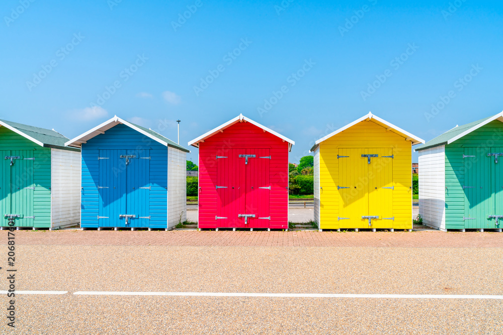 Naklejka premium A row of colorful wooden beach huts on the beach in Eastbourne, East Sussex, UK