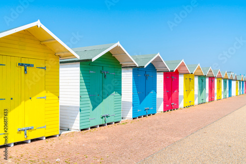 A row of colorful wooden beach huts on the beach in Eastbourne, East Sussex, UK