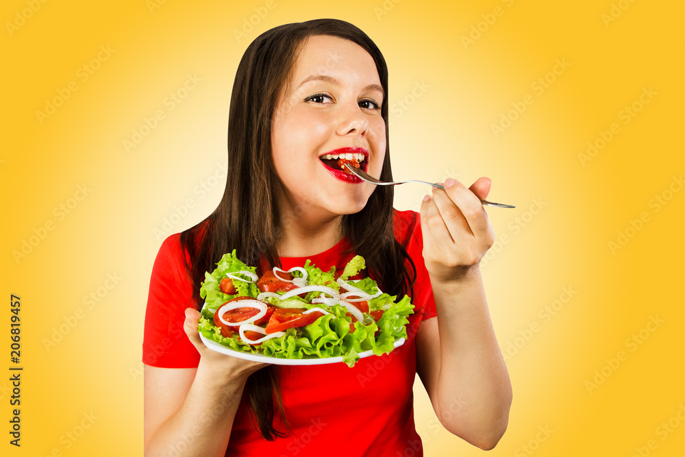 Young woman with excess weight eat salad, isolated on yellow background. Young woman with excess weight eat salad, isolated on yellow background.