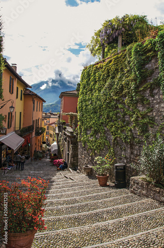 View of alley in hillside, buildings and wall with bindweed in Bellagio, a charming tourist village between the lake and the mountains of the Alps. Located in the Lombardy region, northern Italy