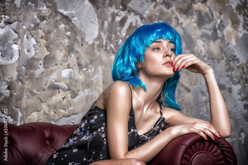 Lady on thoughtful face posing in blue wig, concrete wall background. Woman with blue hair looks unordinary and extraordinary. Freak concept. Lady freak with unordinary appearance photo