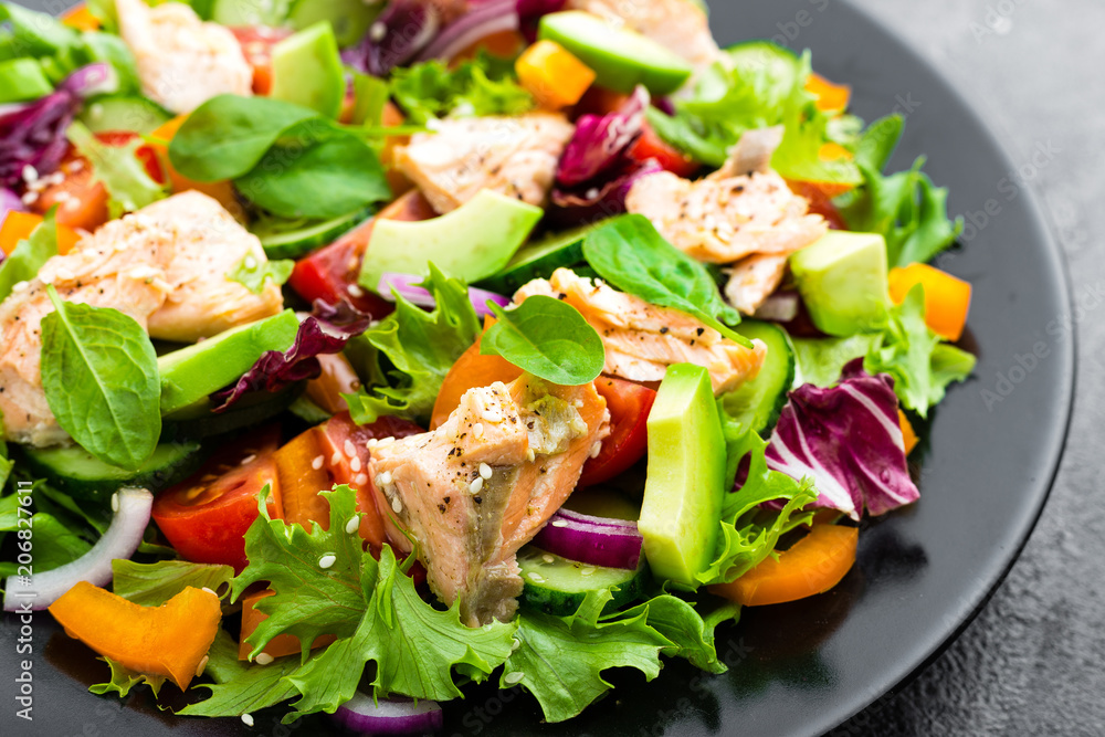 Salad with fish. Fresh vegetable salad with salmon fish fillet. Fish salad with salmon fillet and fresh vegetables on plate Salad with fish. Fresh vegetable salad with salmon fish fillet. Fish salad with salmon fillet and fresh vegetables on plate