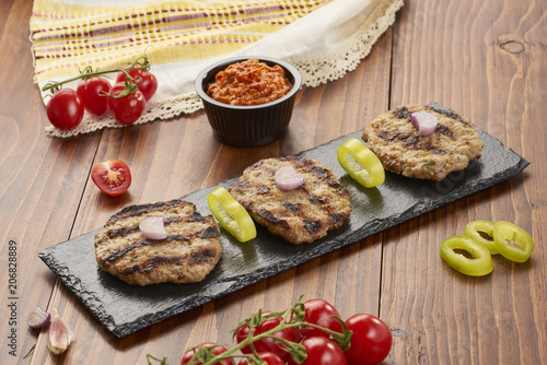 Grilled Veal minced meat with spices on black stone and wooden background 