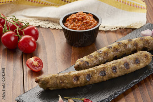 Grilled Veal minced meat with spices on black stone and wooden background  photo