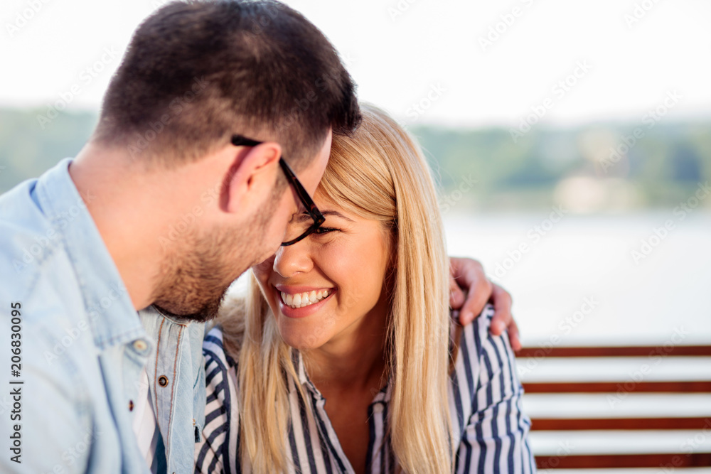 Young couple enjoying time in a riverside cafe. Hugging and touching with foreheads. Young couple enjoying time in a riverside cafe. Hugging and touching with foreheads.