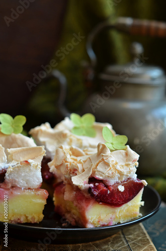 Cake with plums and meringue on a black plate