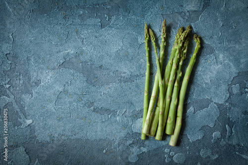Bundle of fresh green asparagus on a stone background with copy space, food health