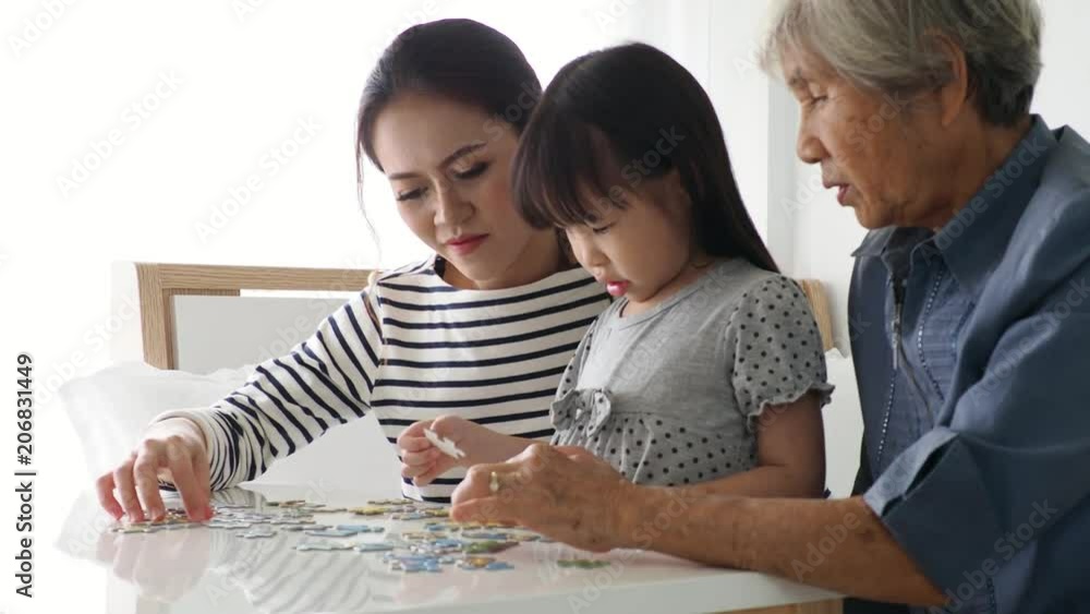 Asian girl doing a puzzle together with her mother and grandmother at home Asian girl doing a puzzle together with her mother and grandmother at home