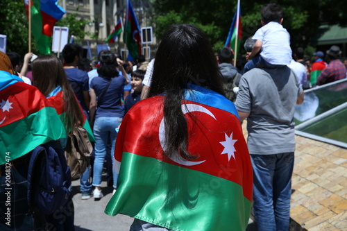 The girl put a flag on his shoulder.Action . Azerbaijan flag in Baku, Azerbaijan. National sign background. Red Green Blue flag. Azerbaijan tradition patriotic. Flags waving wind