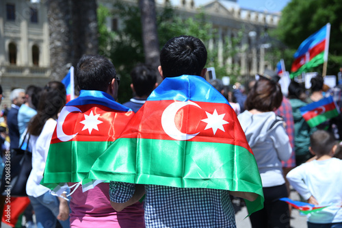 The Azerbaijani flag is on the background of the city . Action . Azerbaijan flag in Baku, Azerbaijan. National sign background. The boy put a flag on his shoulder.