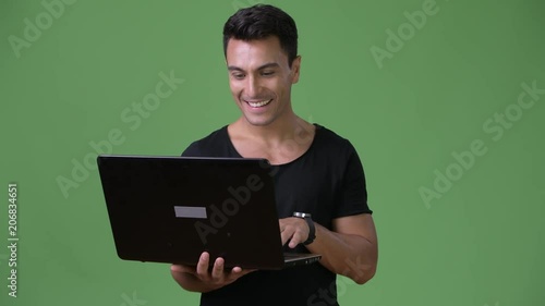 Young handsome Hispanic man against green background