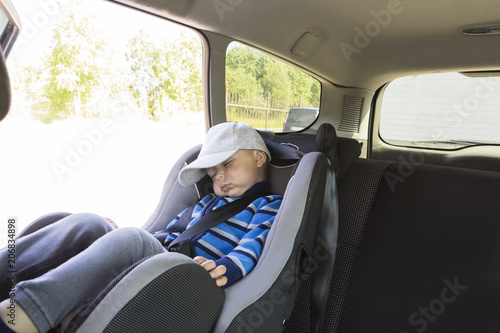boy child sleeping in car seat in car. Road safety.