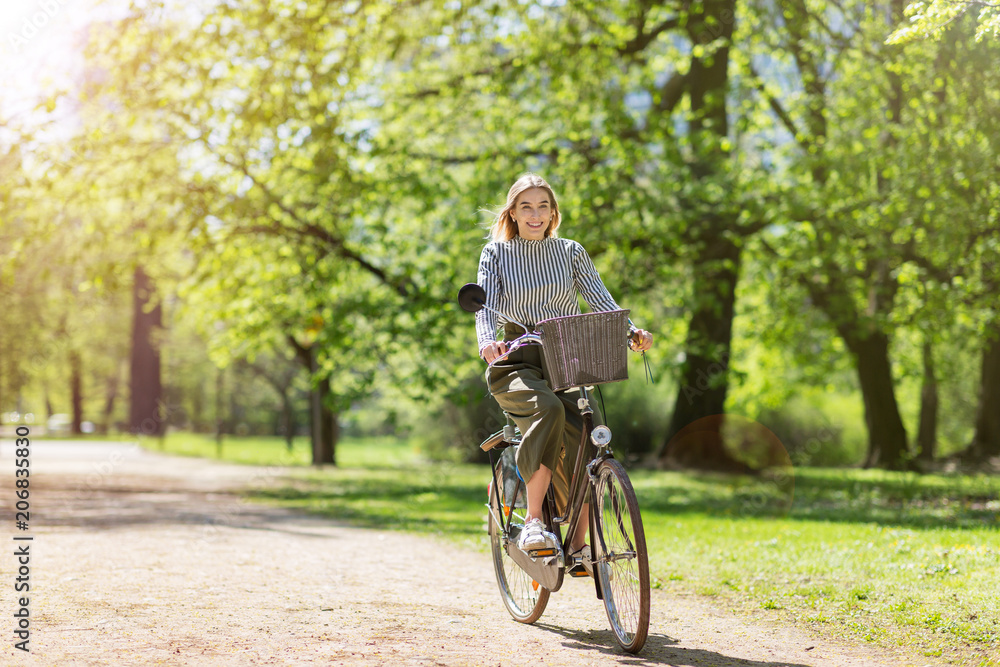 Attractive young woman cycling through the park