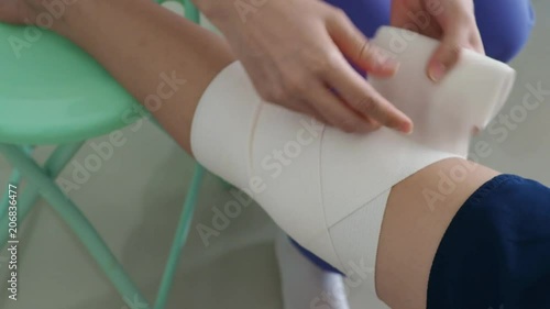 Nurse at the hospital bandaging the knee with a medical bandage for young boy
