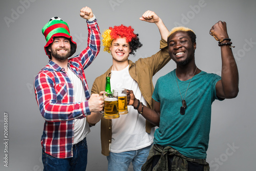 Three young cheerful men holding beer and celebrating isolated over white background