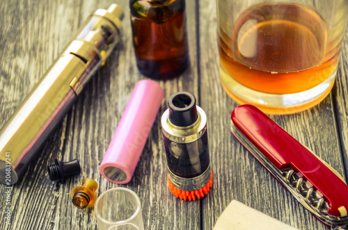 Still life with e-cig and jiuce on the wooden background photo