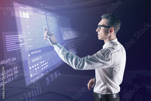 Worried programmer. Clever professional programmer pointing to the information on a transparent screen and feeling worried