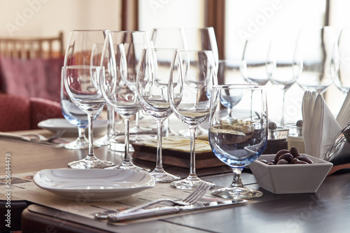 Elegant dishware and wine glasses on the table in the interior