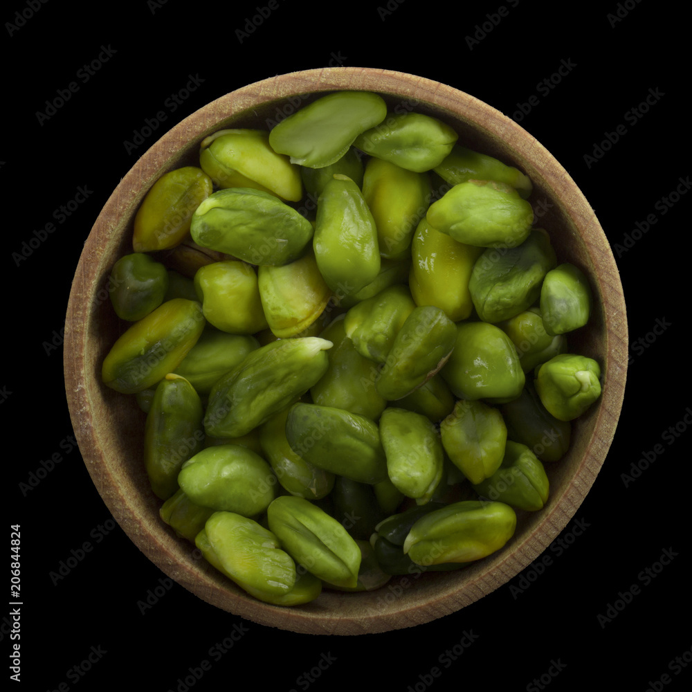 shelled green pistachio in wooden cup isolated on black background. top view shelled green pistachio in wooden cup isolated on black background. top view