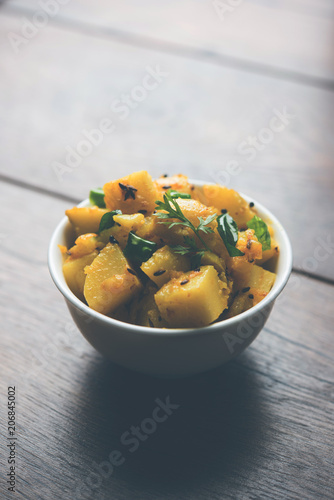 Chatpate Masala Aloo Sabzi fry OR Bombay potatoes served in a bowl, selective focus photo