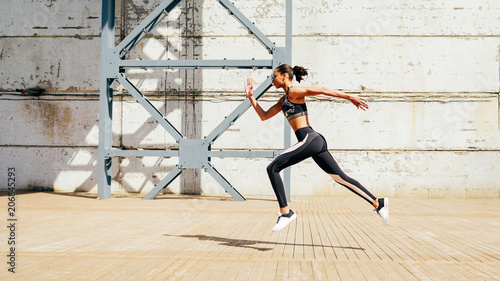 Fotografi Sportswoman jumping forward while sprinting, doing morning exercises