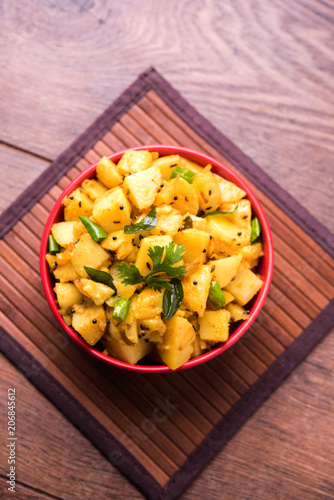 Chatpate Masala Aloo Sabzi fry OR Bombay potatoes served in a bowl, selective focus photo