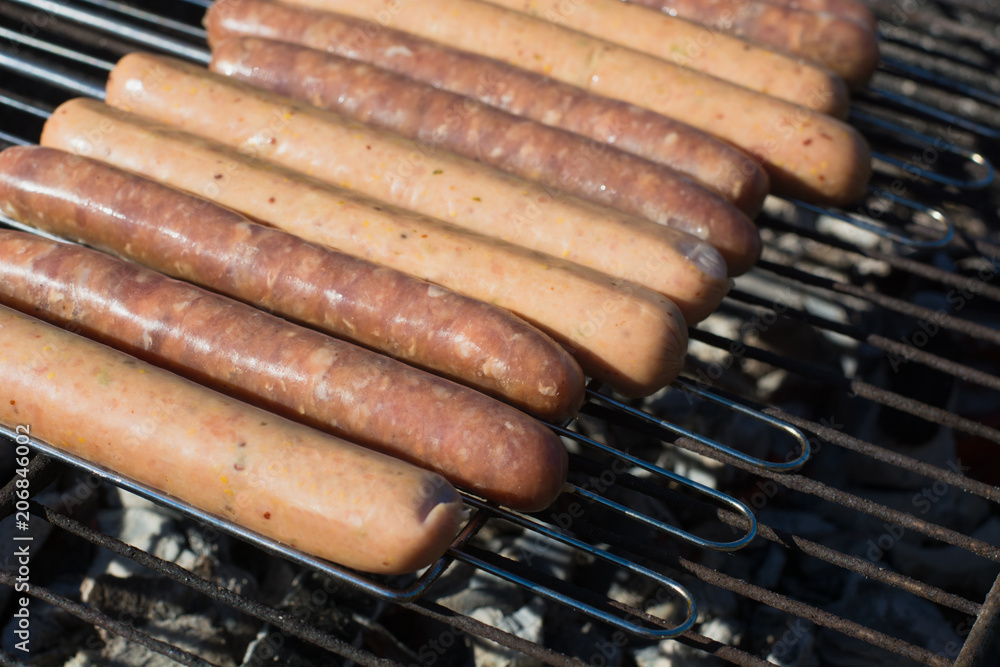 Start cooking. Spicy sausages grilling on portable barbecue on summer picnic. Outdoors. Start cooking. Spicy sausages grilling on portable barbecue on summer picnic. Outdoors.