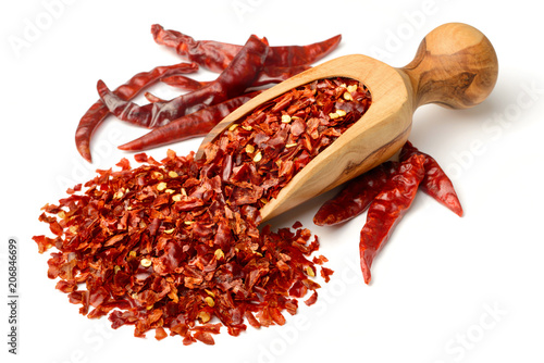 Vászonkép dried red pepper flakes in the olive wooden scoop, isolated on white