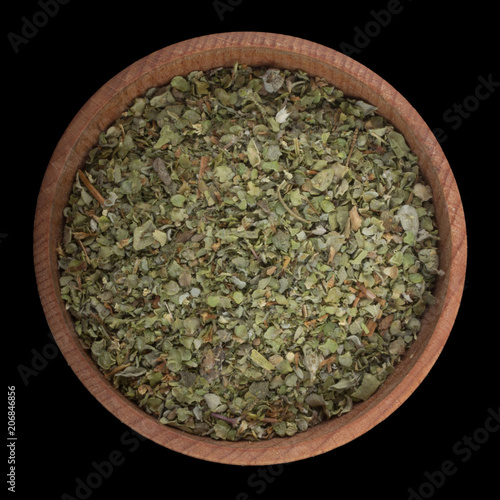 dried ground marjoram in wooden cup isolated on black. top view