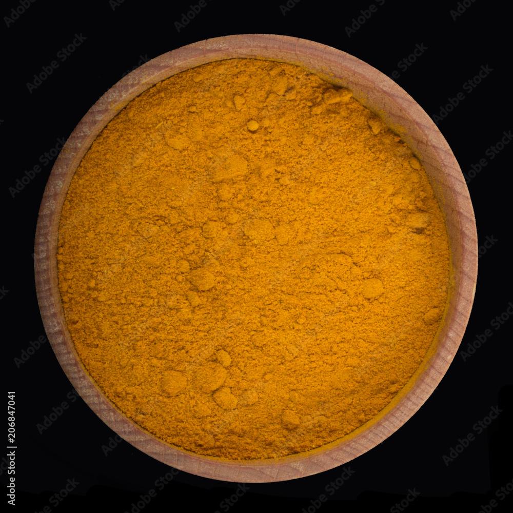 turmeric powder in wooden cup isolated on black. top view