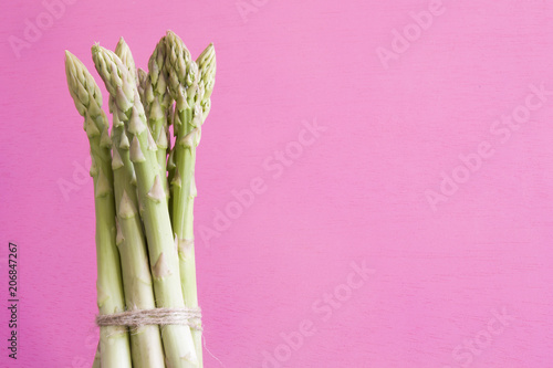 fresh asparagus on a pink wooden background and text space