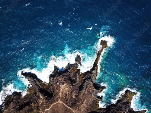 Top view of a deserted coast. Rocky shore of the island of Tenerife. Aerial drone footage of sea waves reaching shore