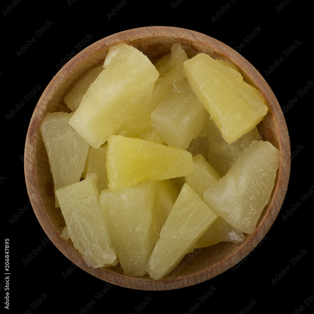slices of pineapples in wooden cup isolated on black. top view slices of pineapples in wooden cup isolated on black. top view